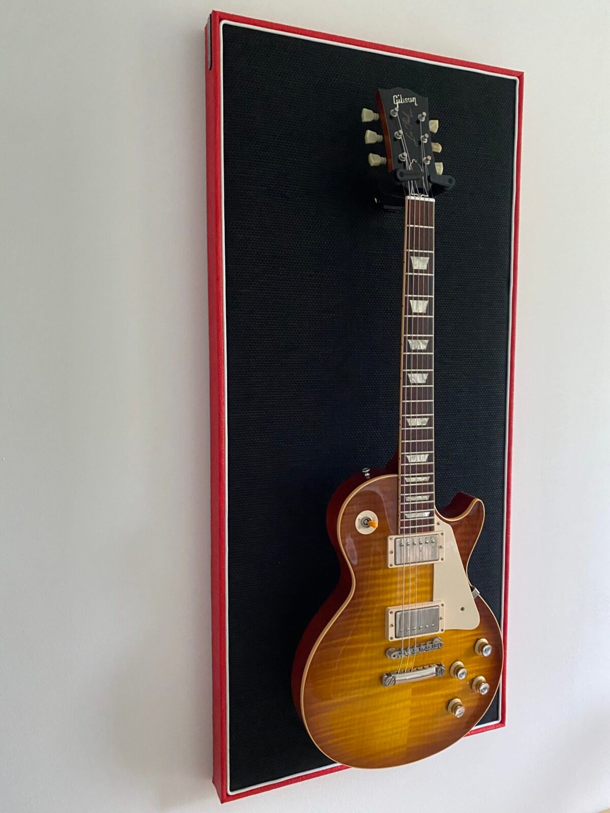 Gitaar aan haak op akoestisch paneel