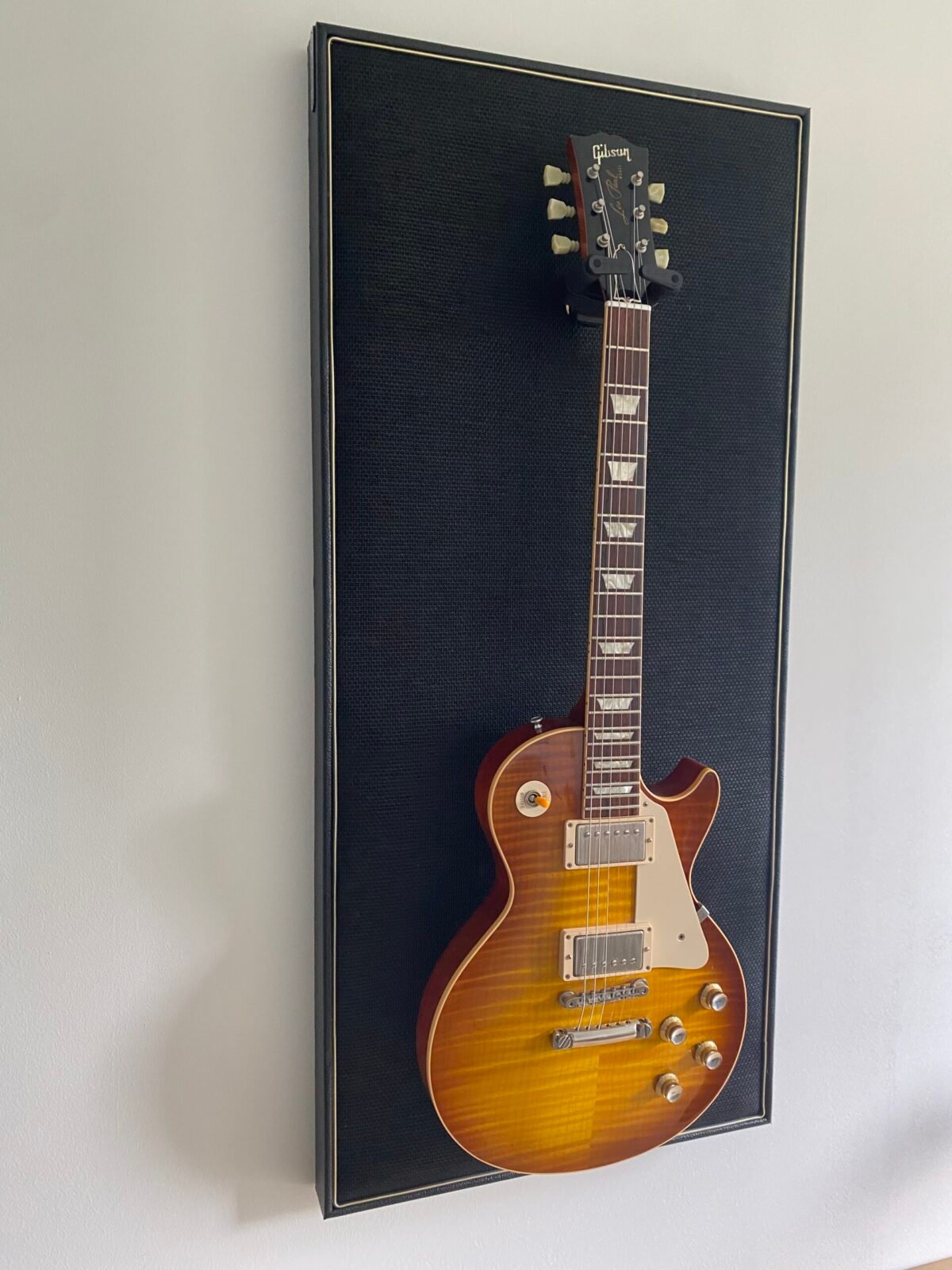 Gitaar aan haak op akoestisch paneel