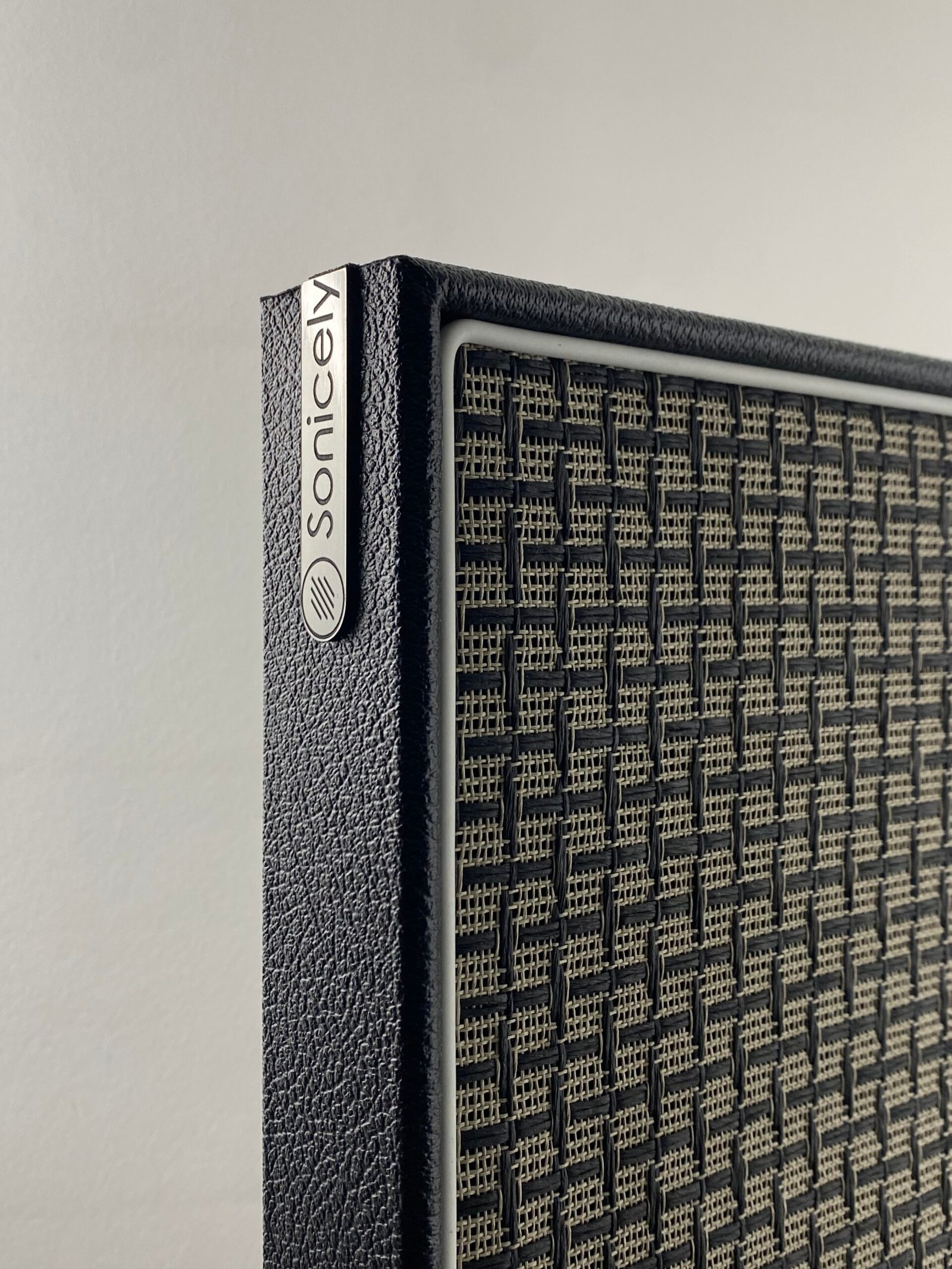 Design akoestische wandpanelen met geïntegreerde gitaarhaak Hoek van akoestisch wandpaneel voor gitaar in zwart met ruit speakerdoek